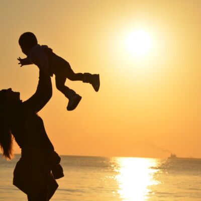 woman-carrying-baby-at-beach-during-sunset-51953